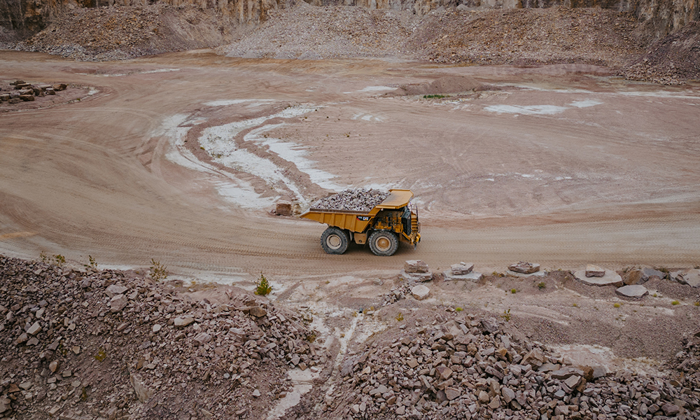 A full dump truck of gravel travels the bottom of the spencer quarry open pit