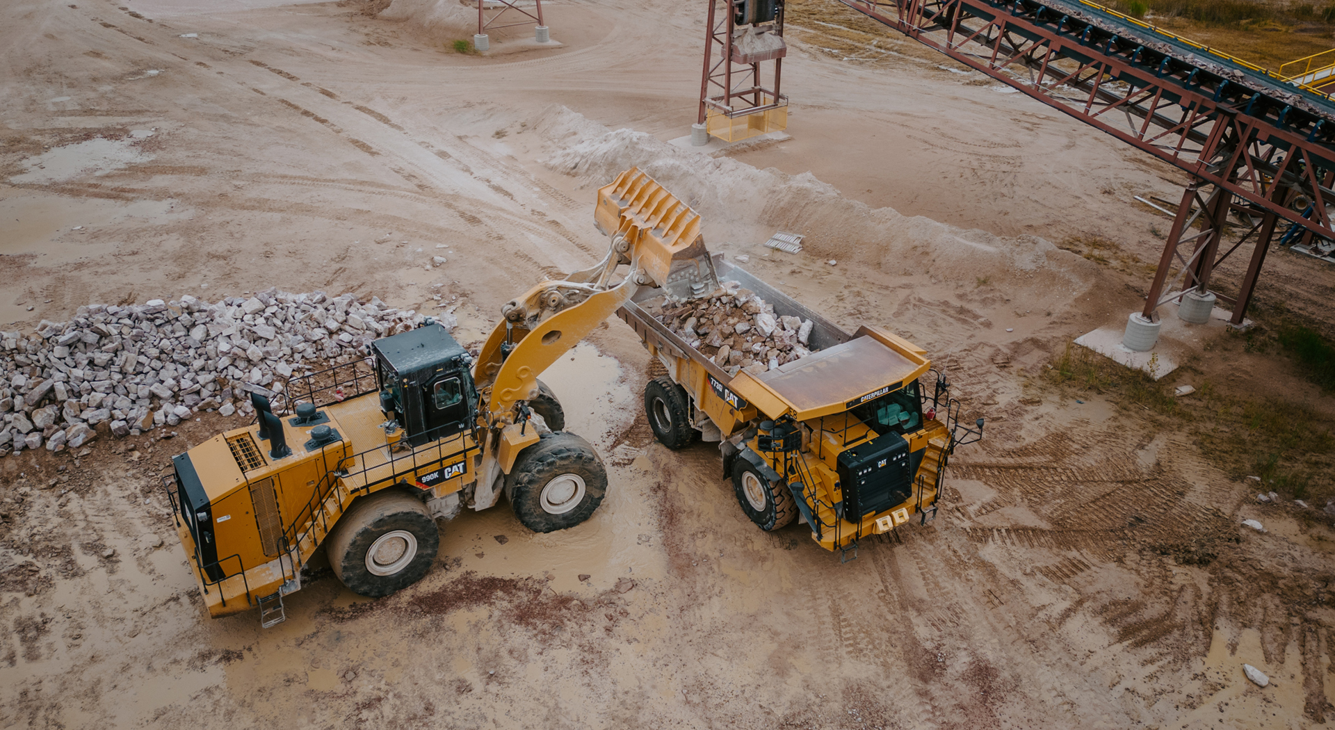A bulldozer loads a dump truck with rock material from spencer quarry